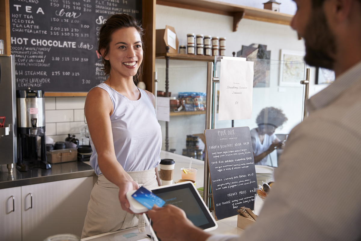 Customer paying with a card at a coffee shop counter